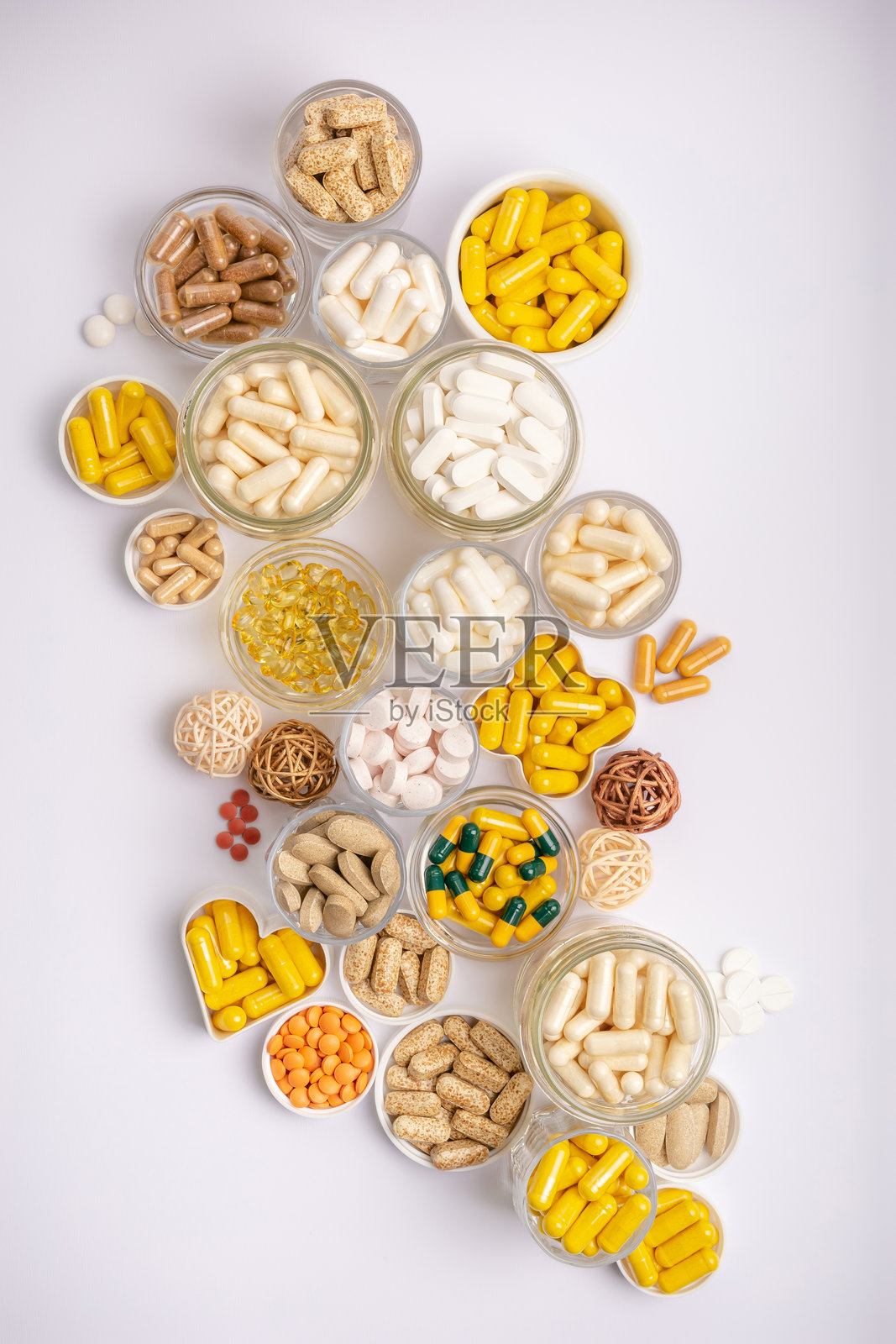 俯视角度拍摄的彩色药丸、片剂和胶囊状的营养补充剂、矿物质和维生素，装在小罐子里，背景为白色。大量的维生素。照片摄影图片