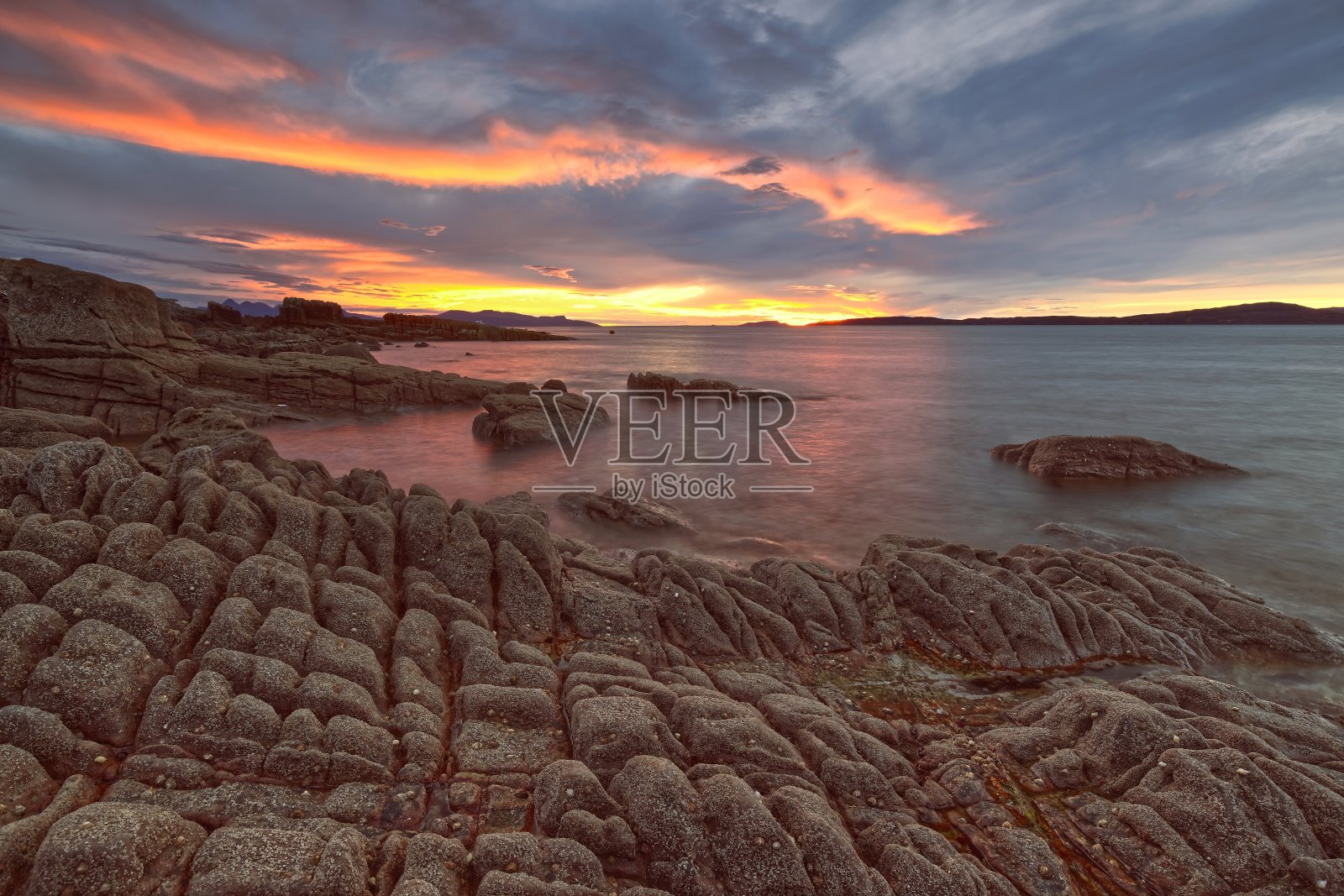 日落时分，色彩斑斓的晚霞将斯凯岛 Strathaird 半岛 Elgol 村的洛赫·斯凯格海湾和岩石海滩染成一片橘红。照片摄影图片