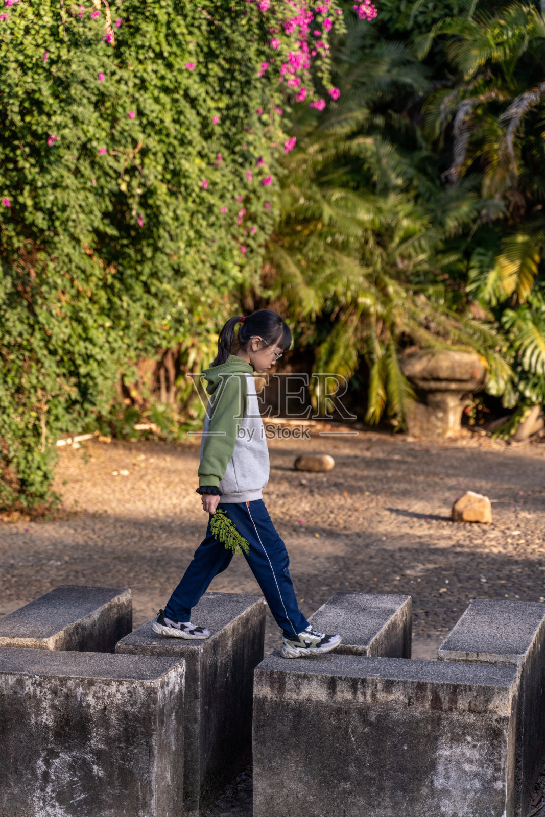 一位亚洲女孩正在公园的树林里散步。照片摄影图片