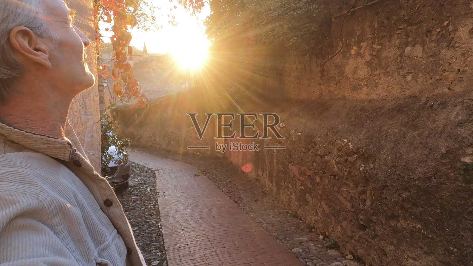 日出时分，一位成熟男子在利古里亚古老村庄的侧影照片摄影图片