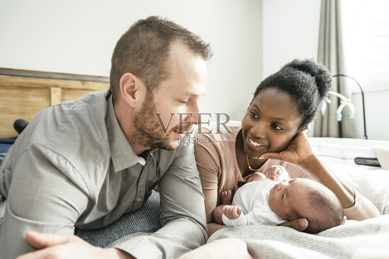 卧室里，一位美丽的母亲正在哺乳她的婴儿，一家人拍摄的肖像照。照片摄影图片