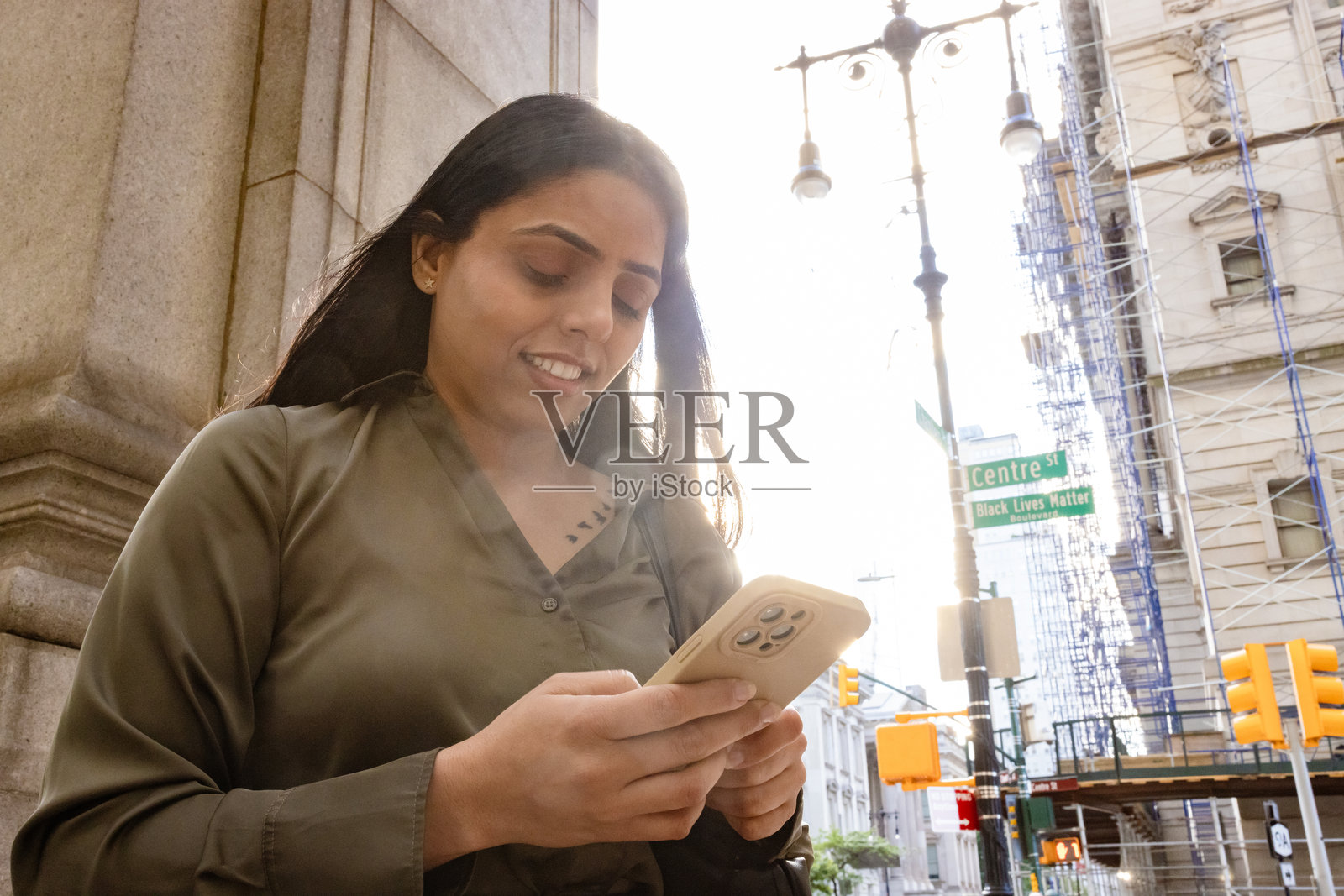 一位女士在户外使用智能手机，脸上带着微笑照片摄影图片