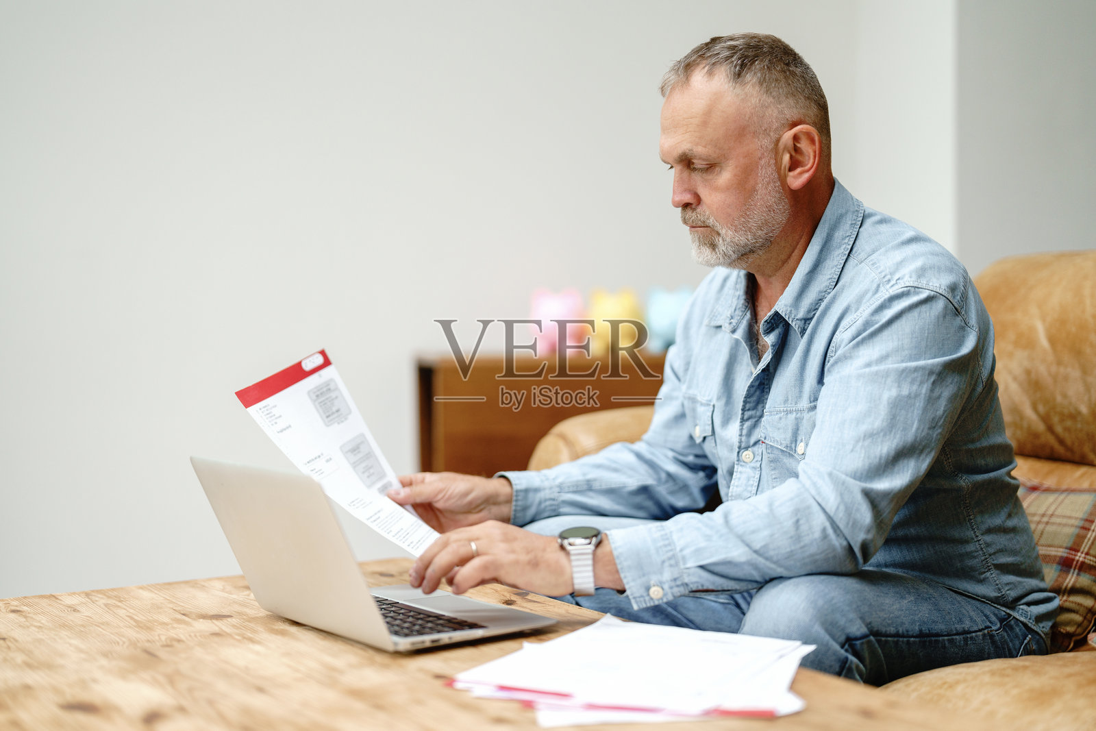 男人在舒适的客厅里用笔记本电脑工作并查阅文件照片摄影图片