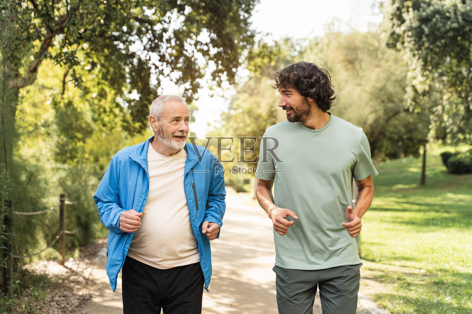 健康的年长男性正在运动，与年轻成年人一起锻炼，在公园跑步时享受交谈照片摄影图片