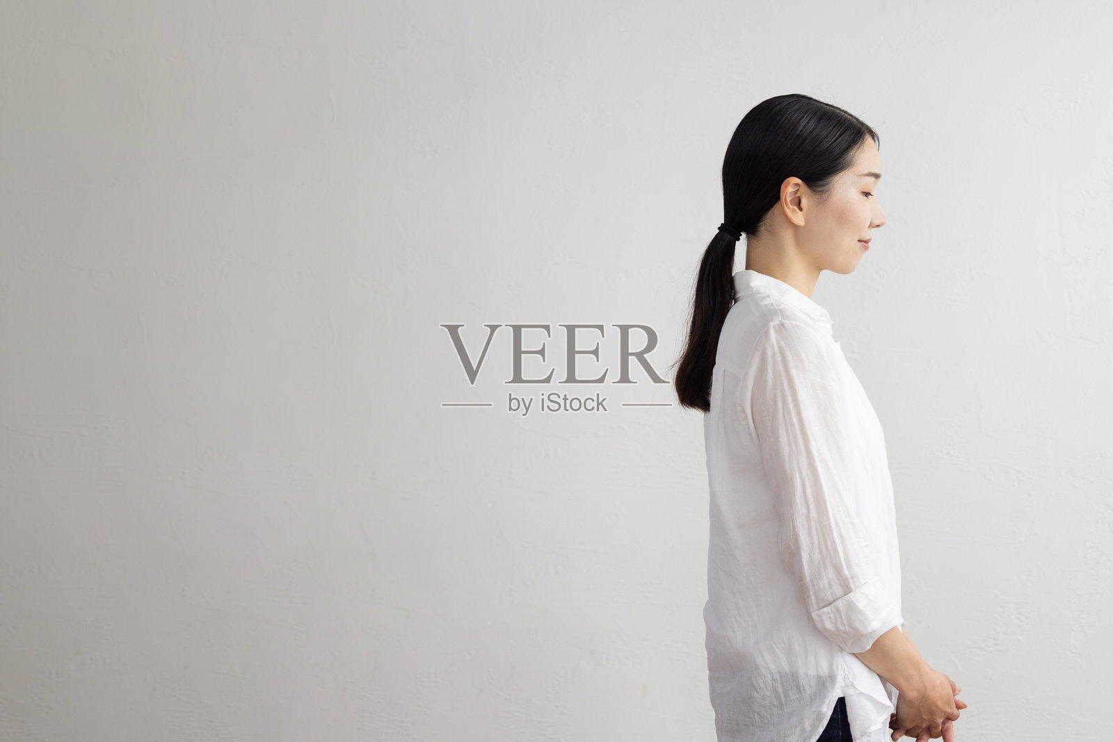 白色背景前站立的女性侧面照照片摄影图片