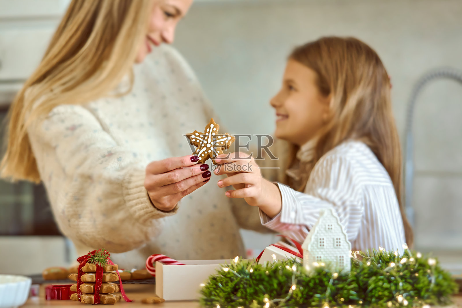 母亲和女儿在家分享圣诞时刻，装饰姜饼星星饼干照片摄影图片