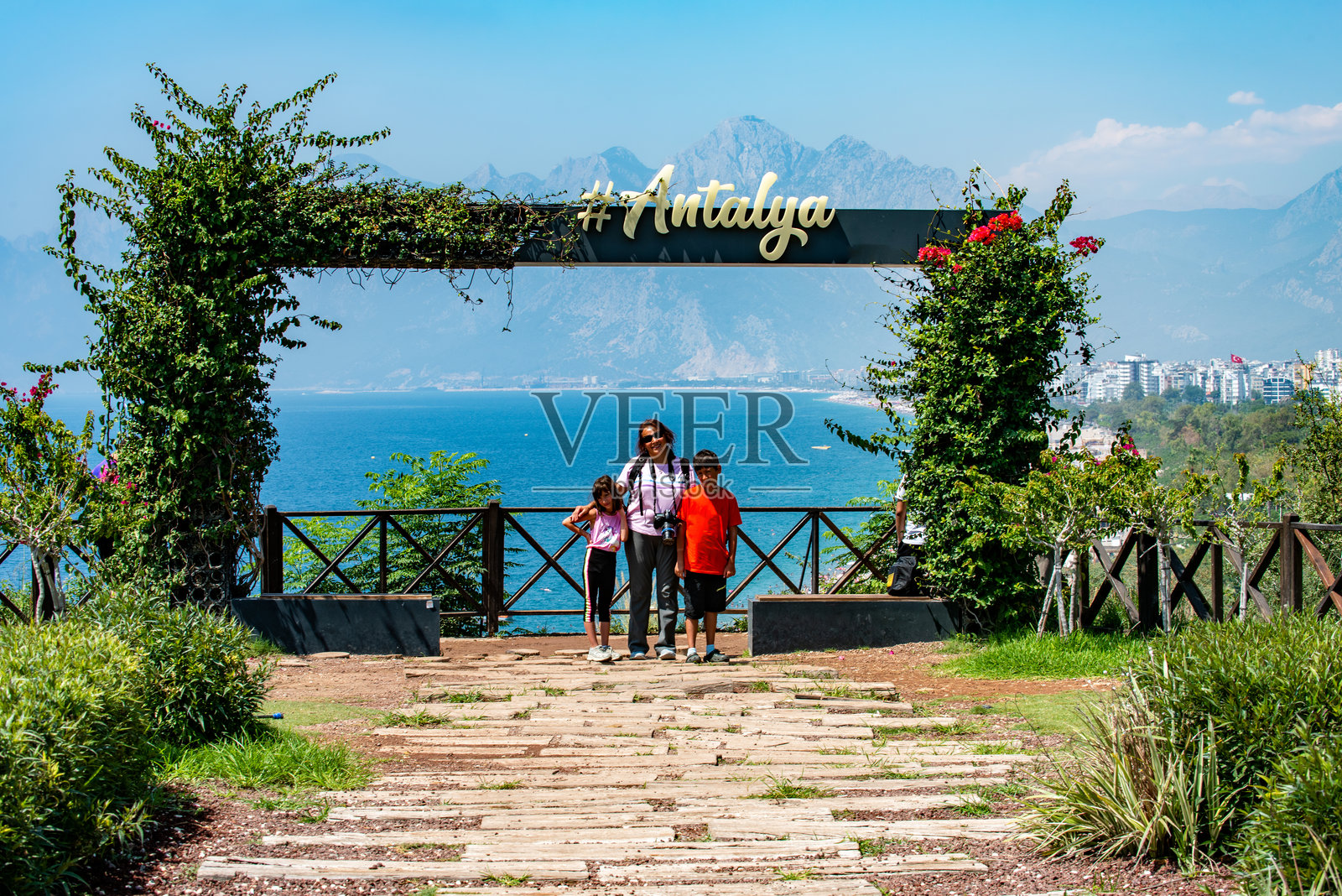 一位母亲和她的两个孩子在安塔利亚标志下的孔亚阿特海滩公共观景点合影照片摄影图片