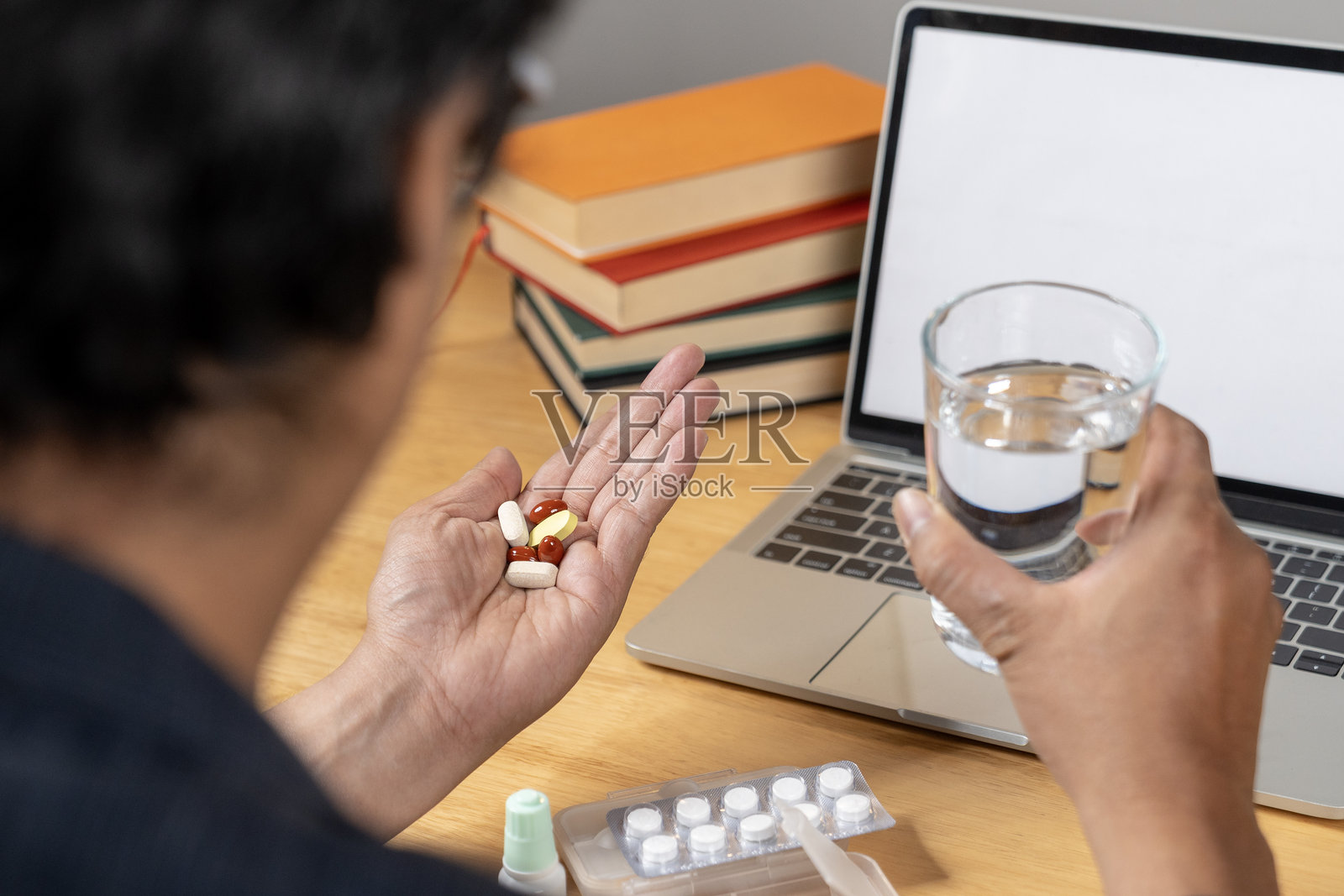 一名商务人士在办公室里拿着一杯水和药片照片摄影图片