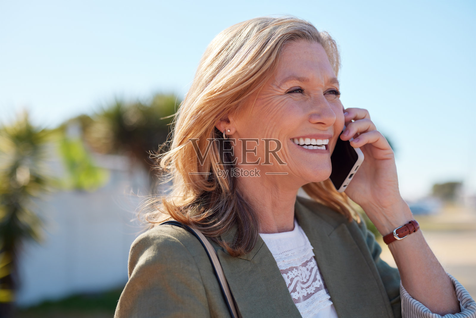 一位成熟的女士在户外接听电话并微笑照片摄影图片