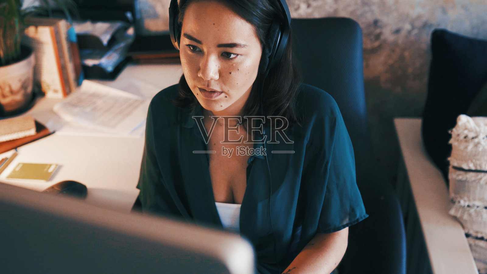 在家办公的职业女性，戴着耳机对着电脑进行文案撰写、文章审阅和编辑。作为自由职业者，她一边听着音乐、音频或声音，一边进行研究，为网站内容或报告工作。照片摄影图片