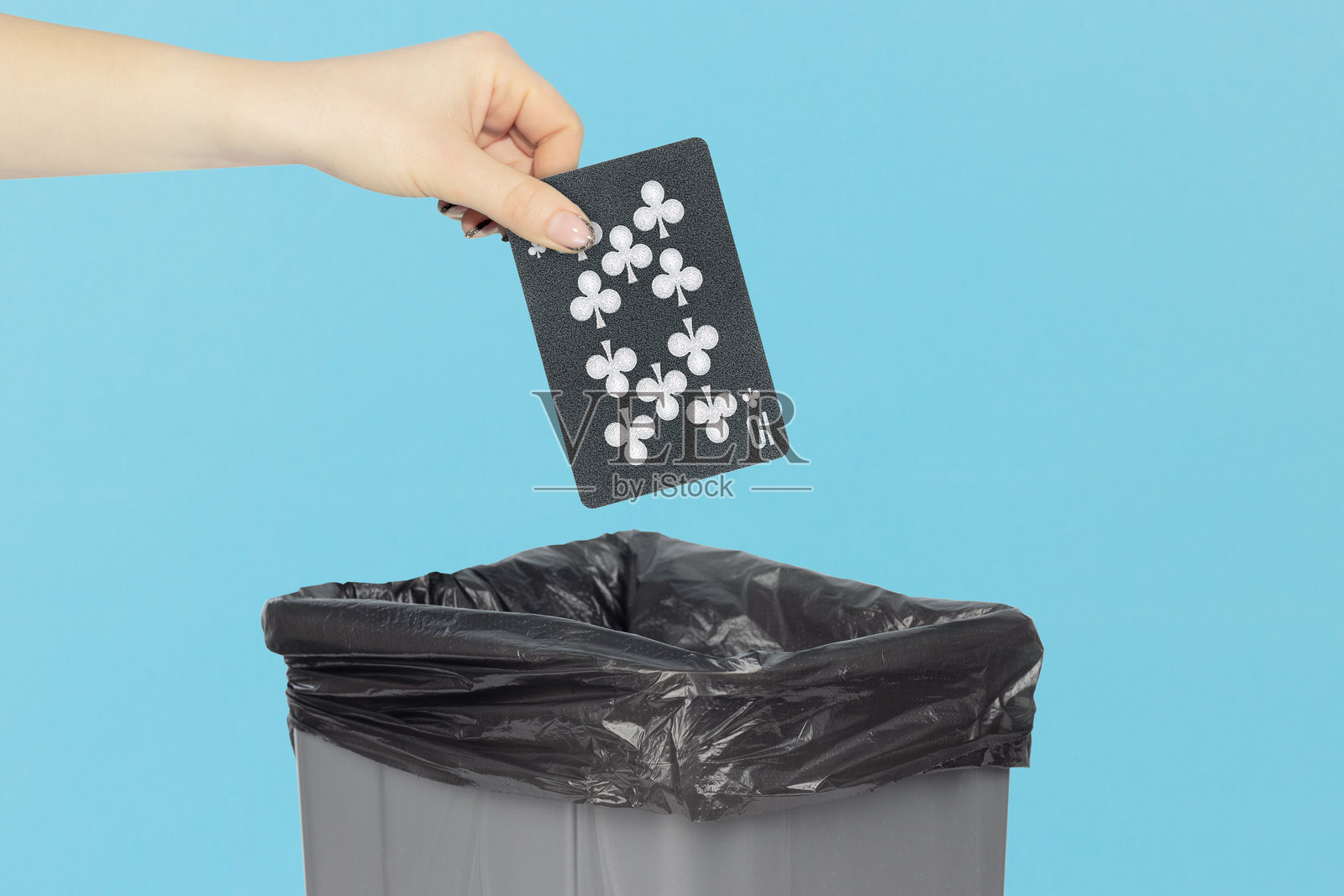 将黑桃10扑克牌扔进垃圾桶，伸出的手拿着扑克牌放在垃圾桶前照片摄影图片