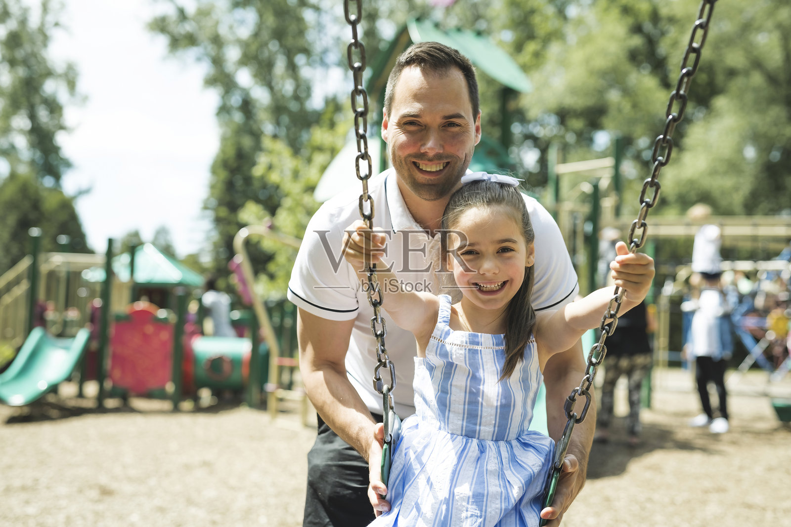 爸爸推着他可爱的女儿荡秋千照片摄影图片