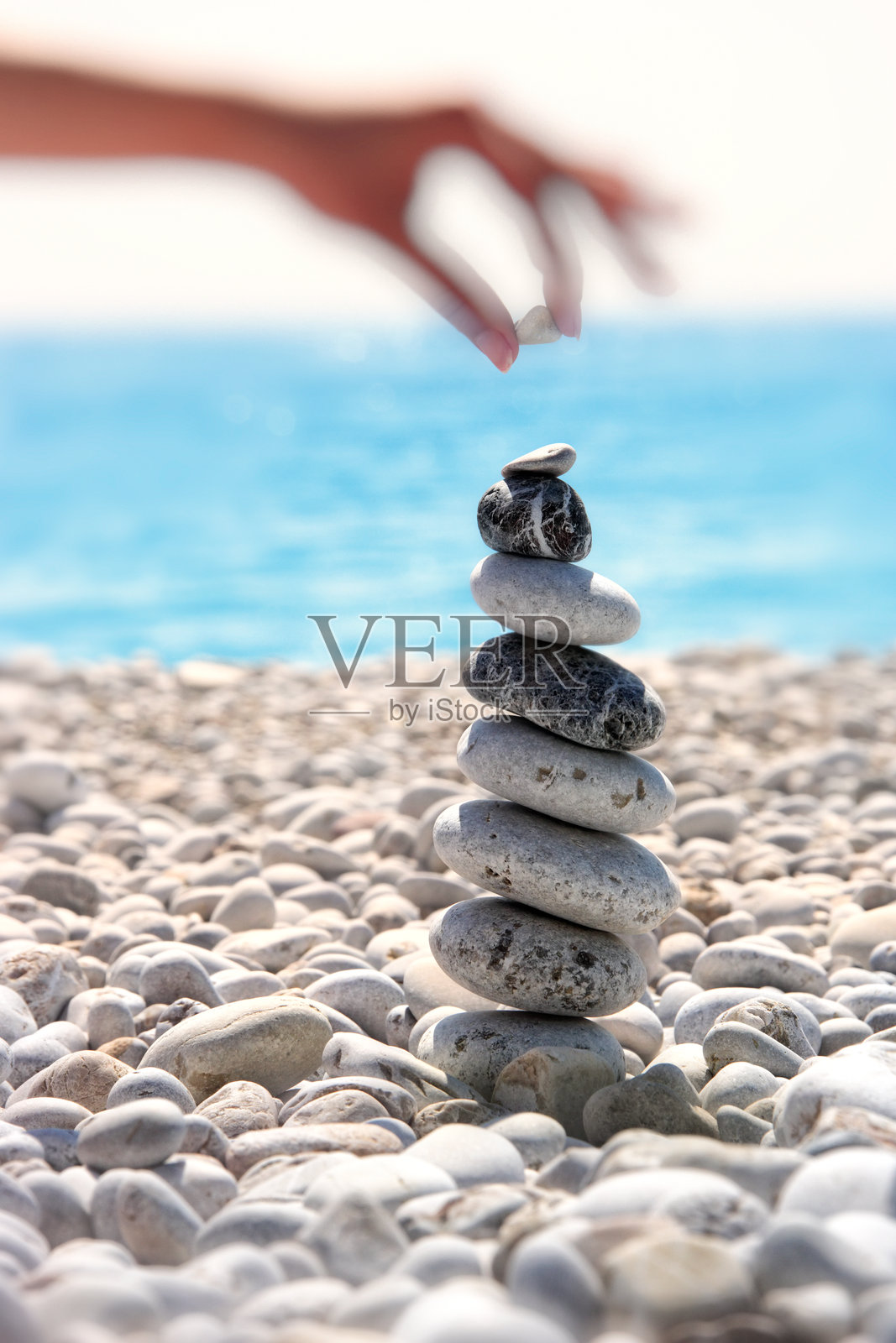 年轻女子在夏日海滩度假时堆叠石头照片摄影图片