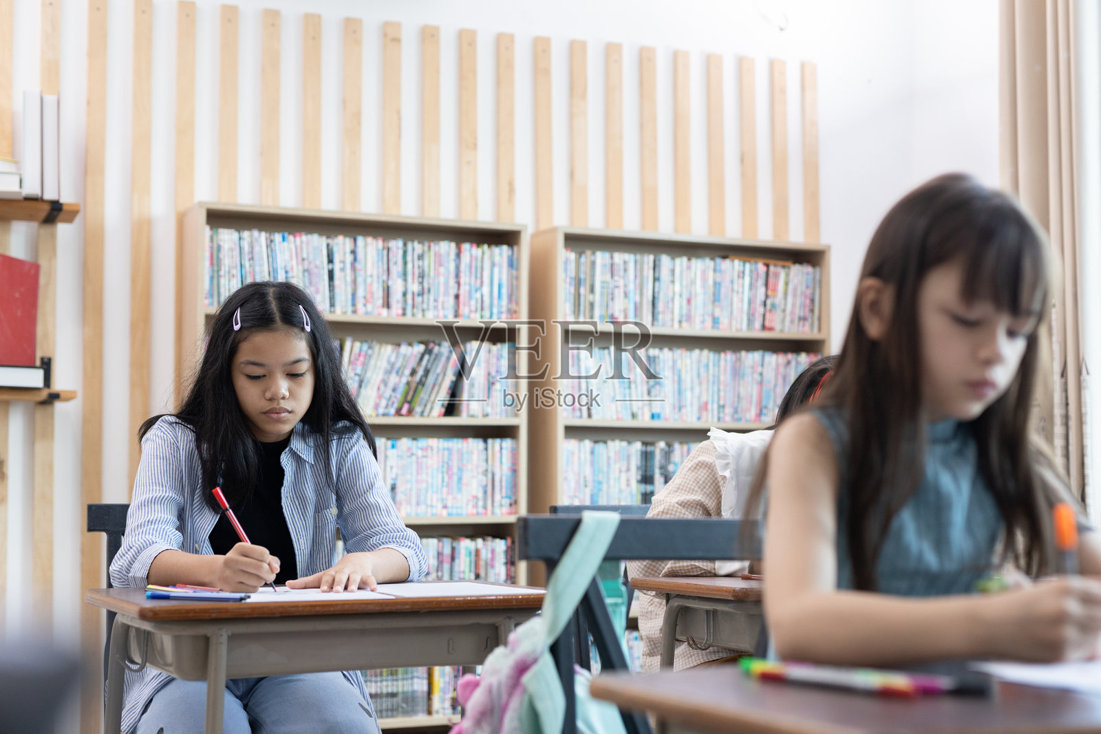 小学生教室教育。快乐学习的女孩。遵照老师指示写作。返校概念。照片摄影图片