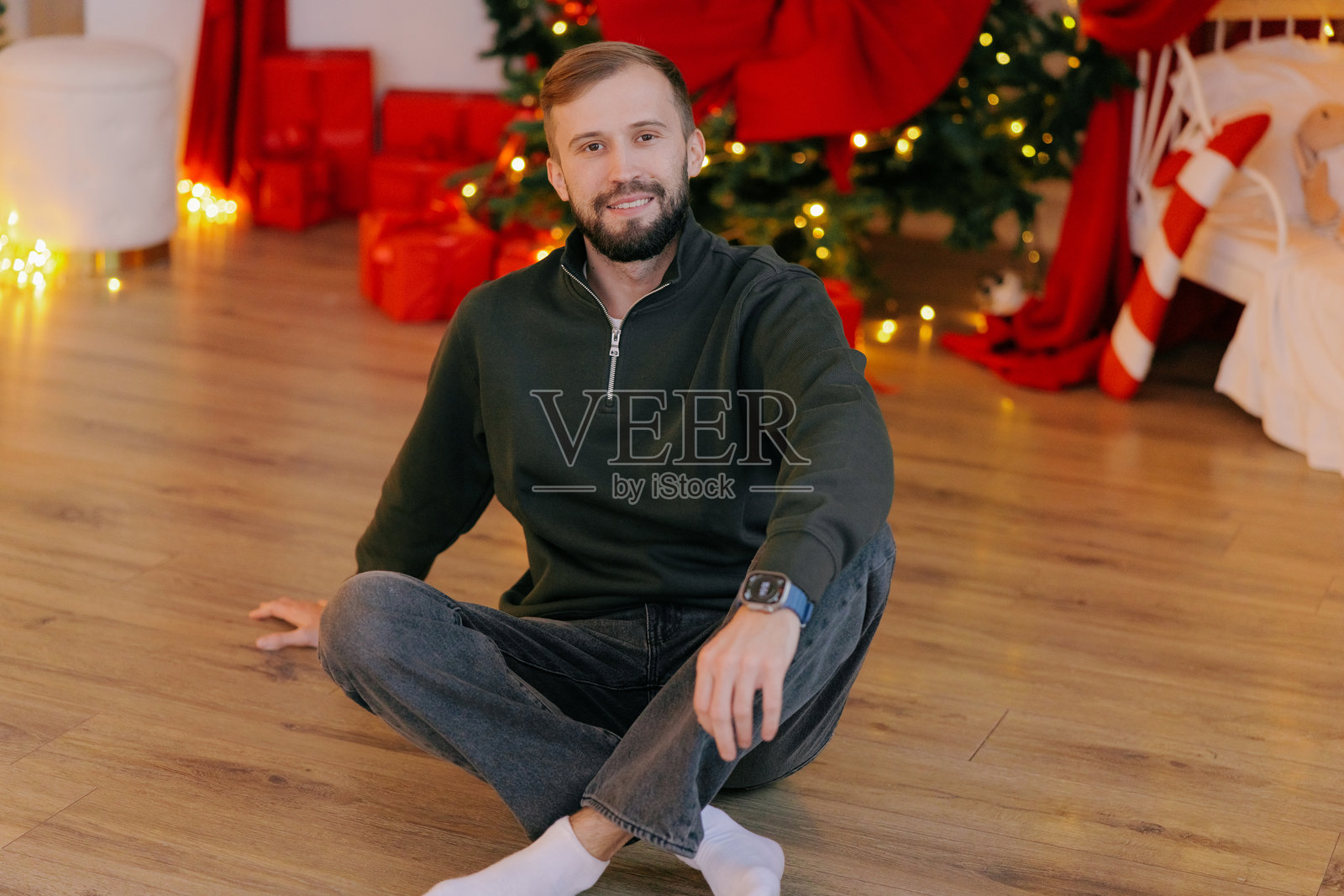 一个快乐的男人坐在地板上，背景是圣诞装饰照片摄影图片