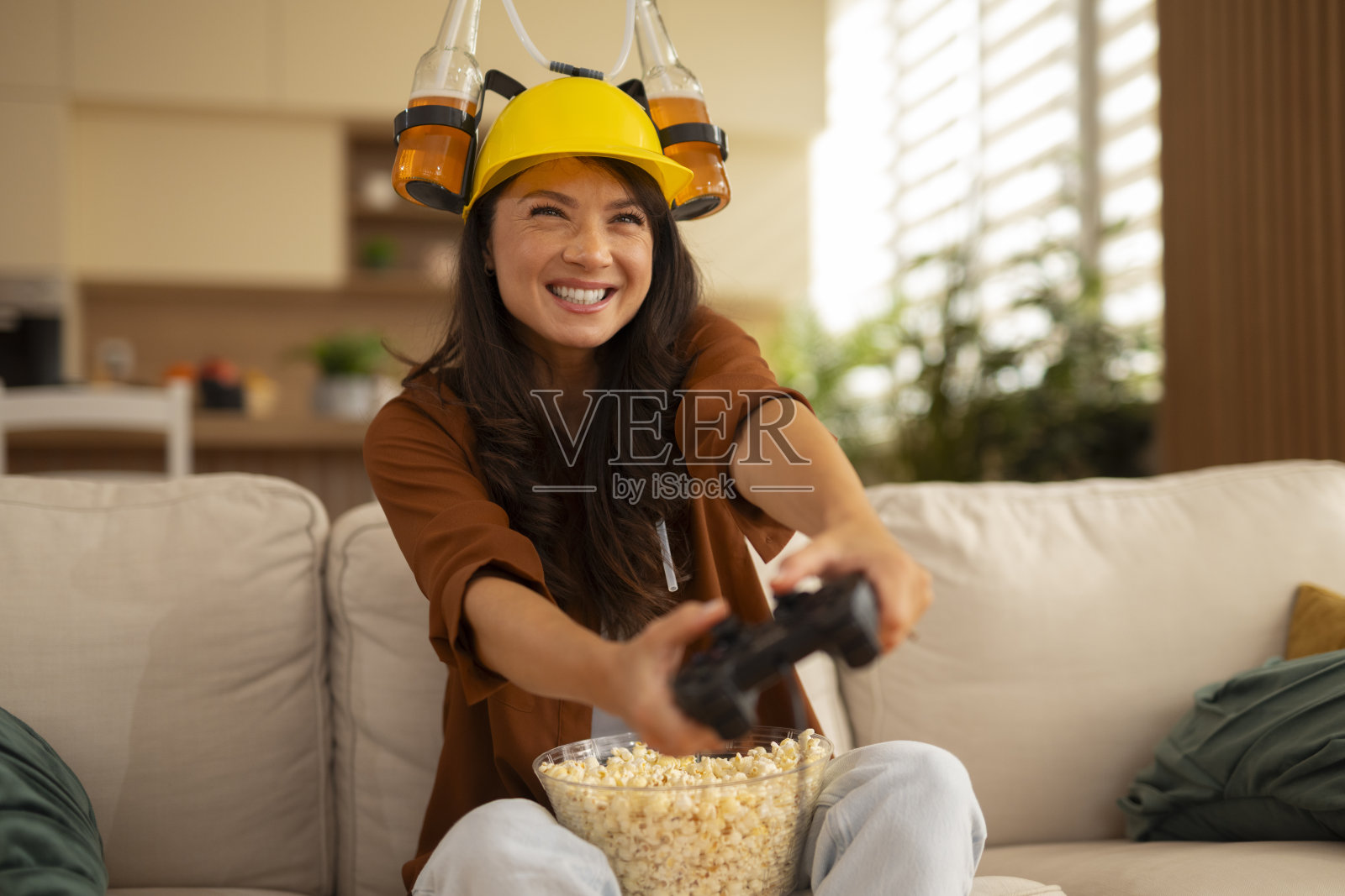 戴着啤酒头盔，兴致勃勃玩电子游戏的女人照片摄影图片