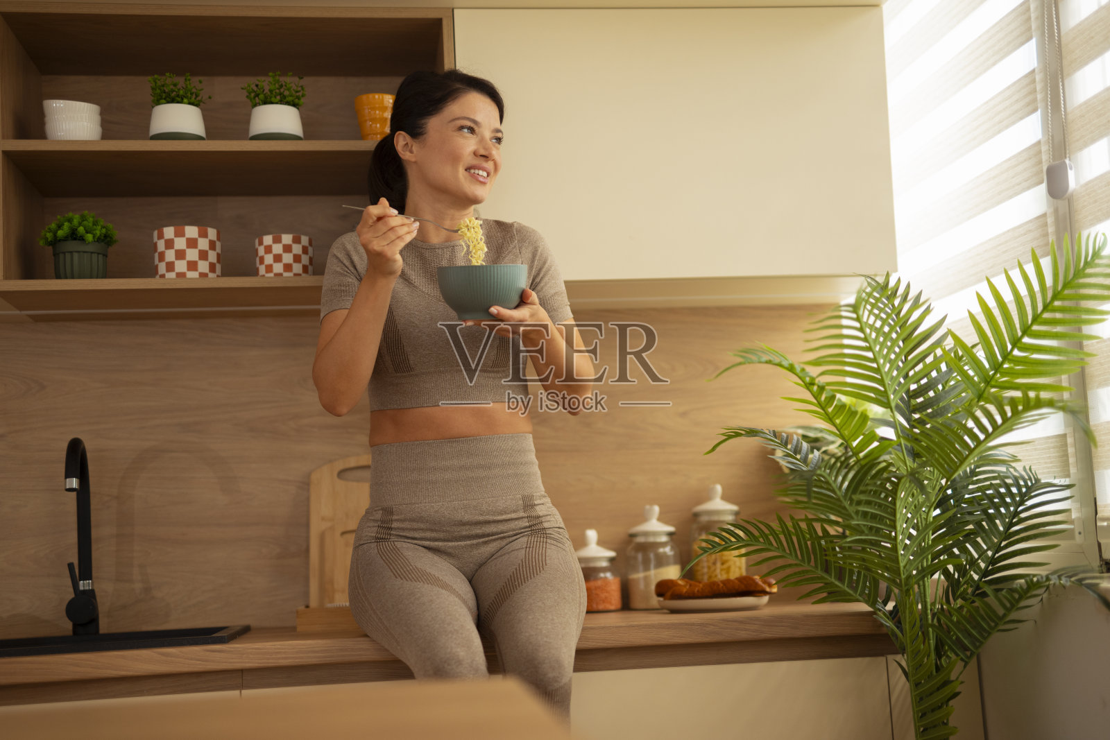 年轻女子在现代厨房享用健康面条照片摄影图片