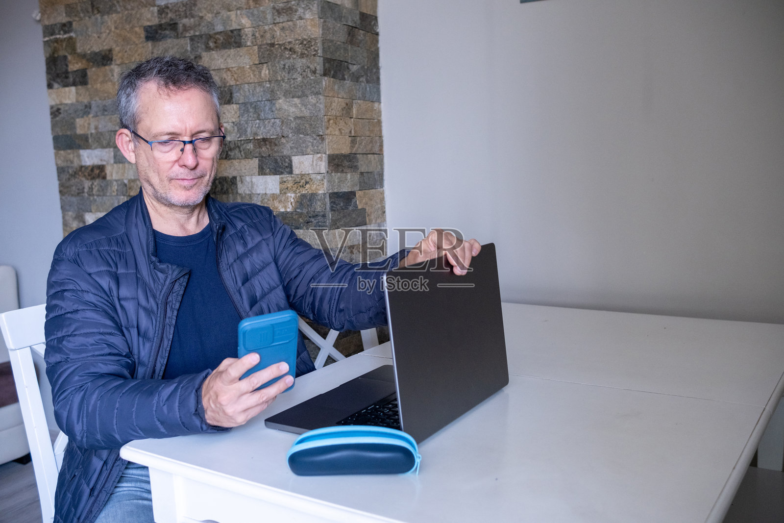 男子在家用笔记本电脑和智能手机远程办公照片摄影图片