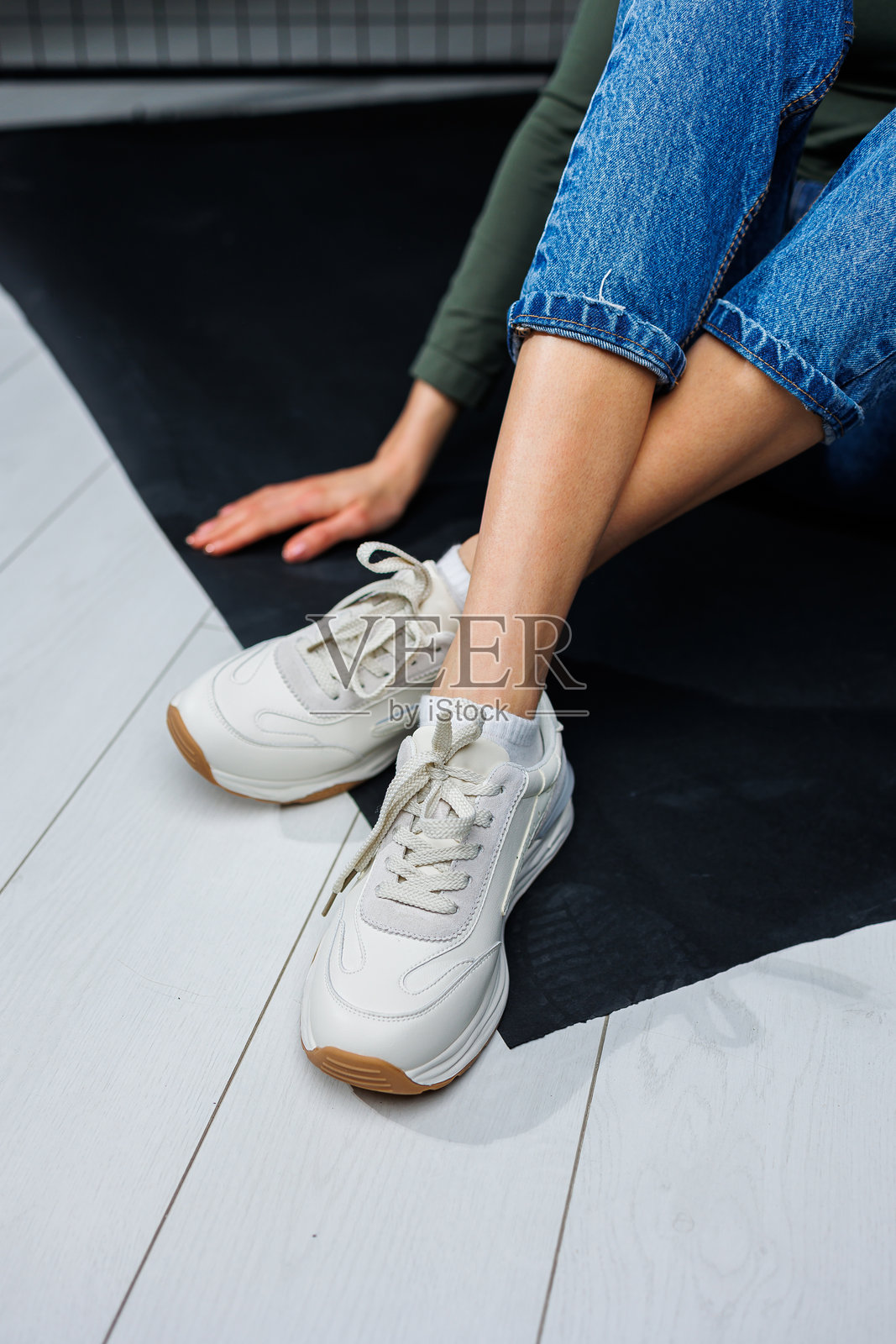 女士运动鞋。穿着牛仔裤和白色时尚休闲运动鞋的纤细女性腿部。舒适的夏季女鞋。休闲女装时尚。照片摄影图片