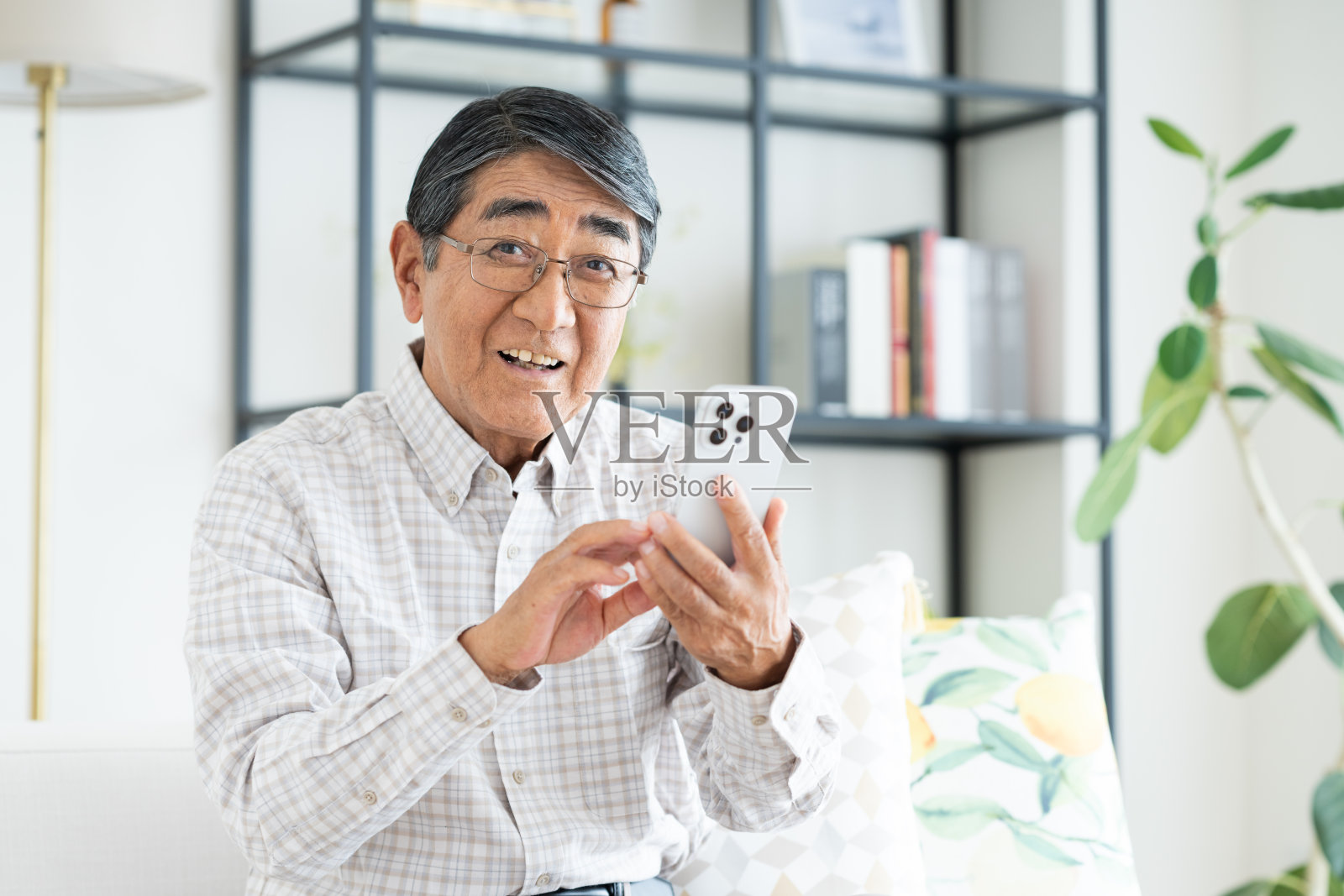 一位年长的男士在客厅里使用智能手机照片摄影图片