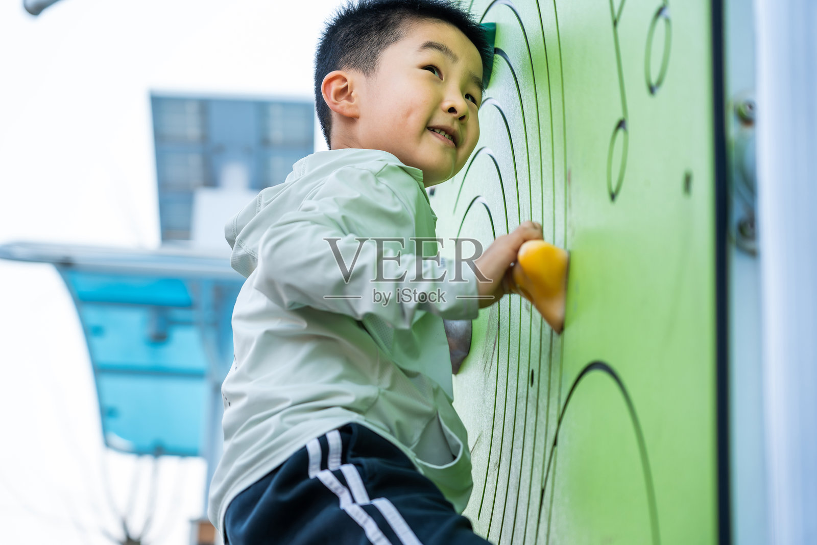 男孩在户外的彩色攀岩墙上攀爬照片摄影图片