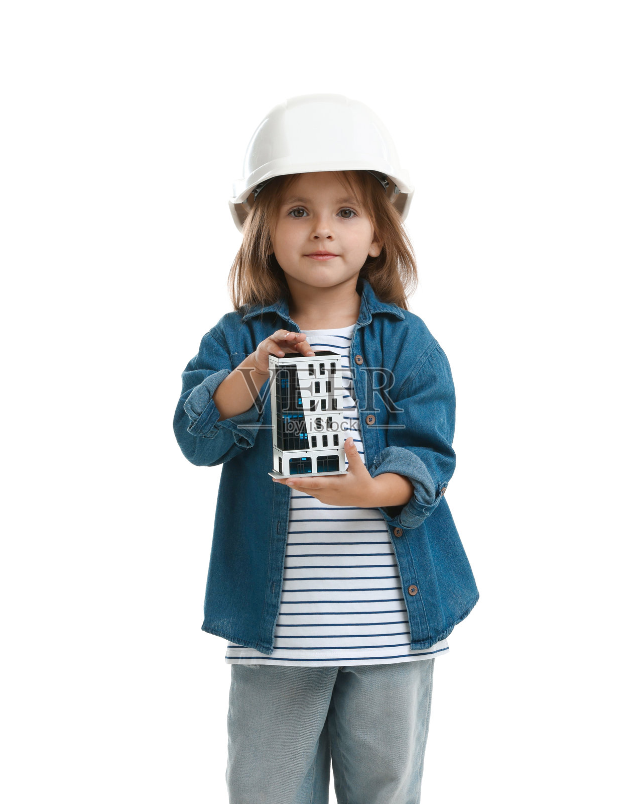 职业选择。戴着安全帽的小女孩拿着建筑模型，在白色背景上假装自己是建筑师照片摄影图片