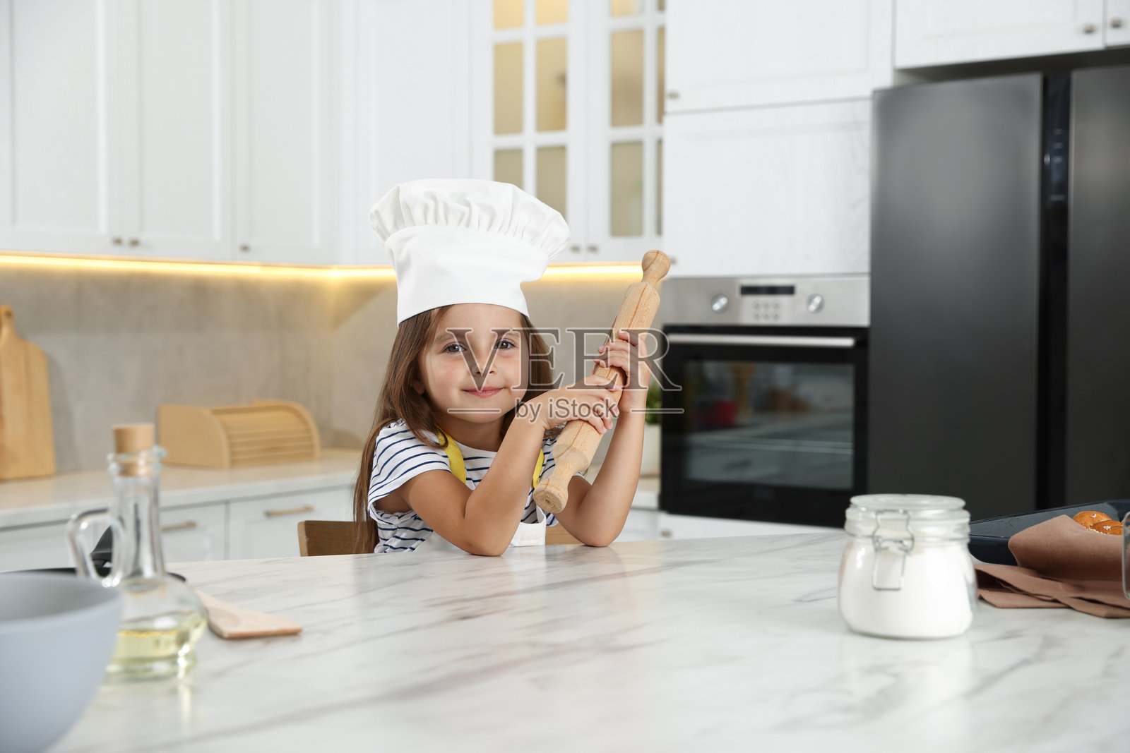 职业选择。小女孩在厨房里拿着擀面杖假装是厨师照片摄影图片