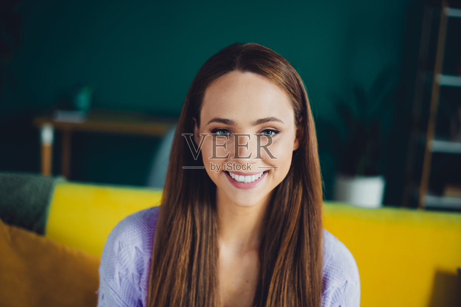 一位年轻的棕发女子，笑容温暖，身处色彩缤纷的客厅，适合生活方式、家居内饰和房地产图库照片照片摄影图片