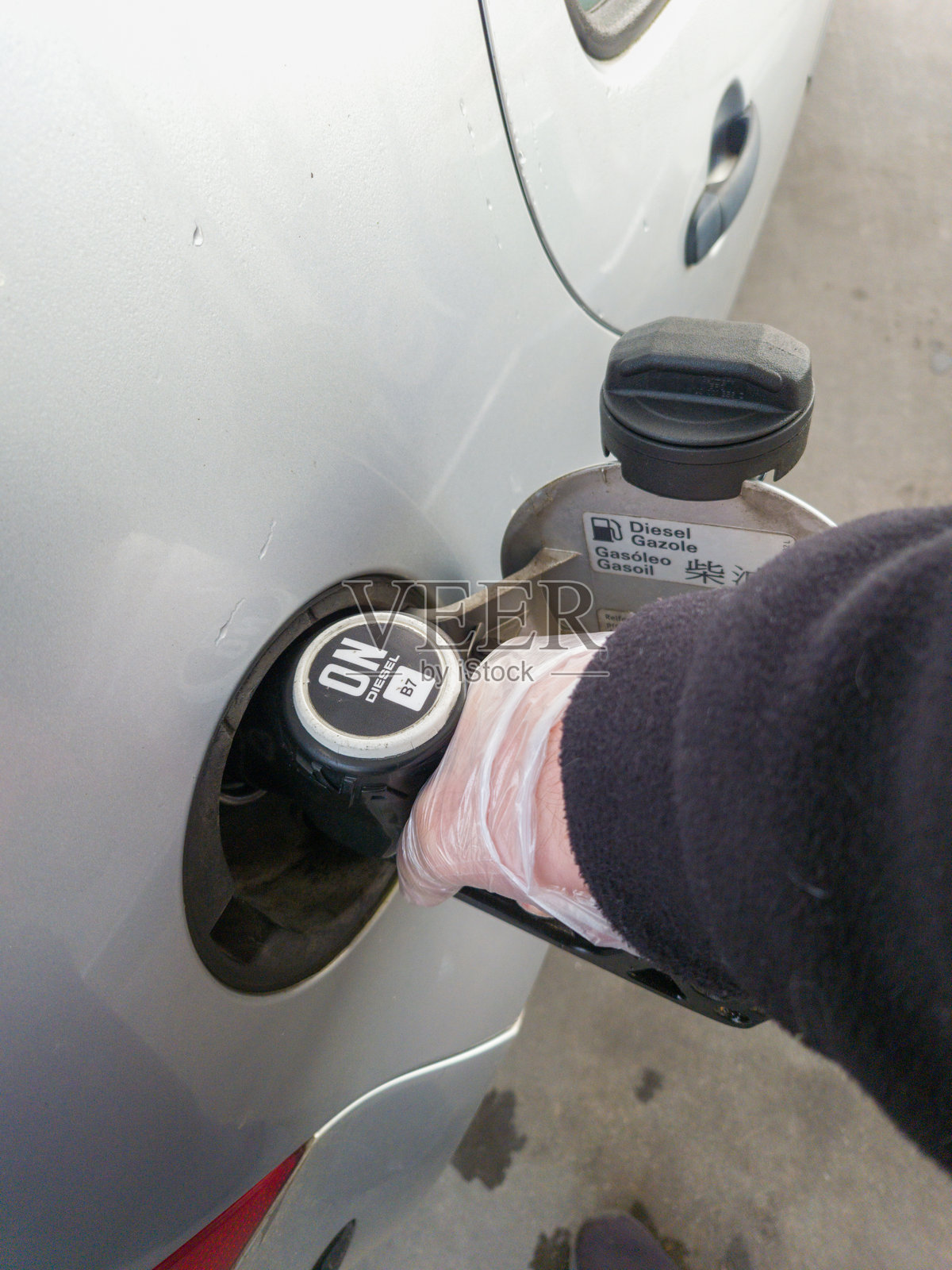 加油站，一个人正在用油枪给柴油汽车加油。照片摄影图片