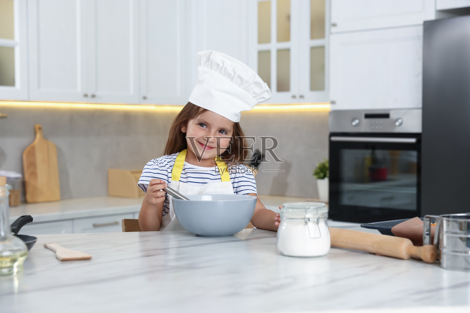 职业选择。小女孩在厨房里假装厨师照片摄影图片