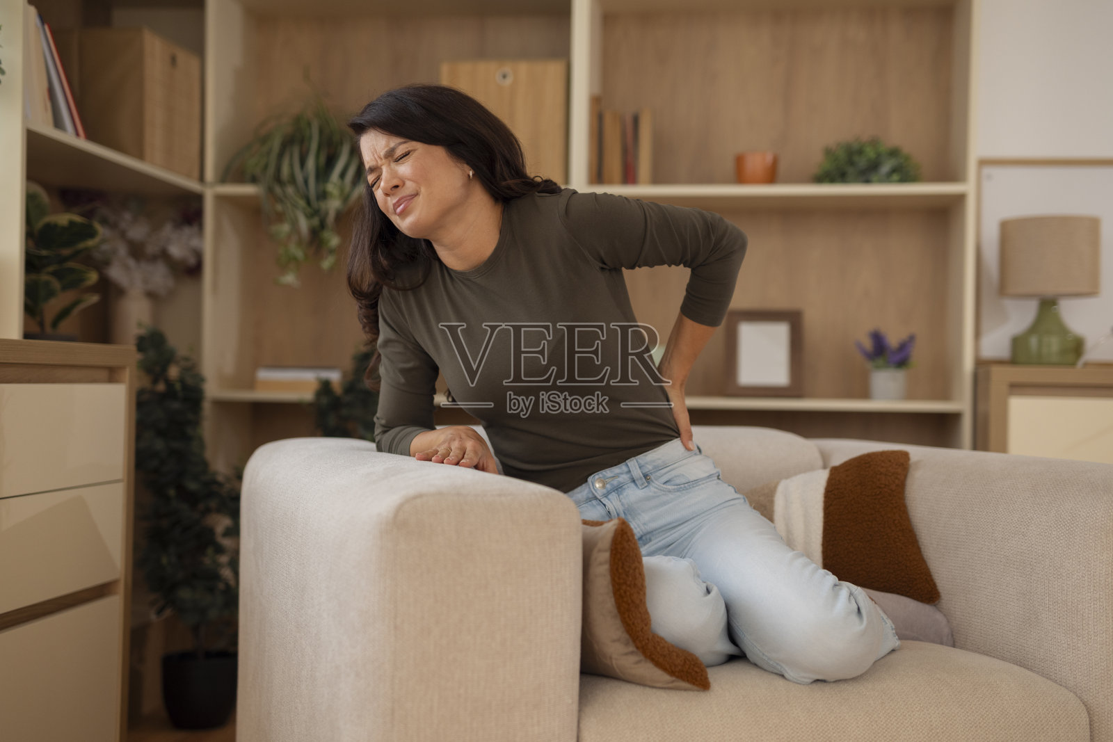 一名女性在家中遭受背部疼痛，感到不适照片摄影图片