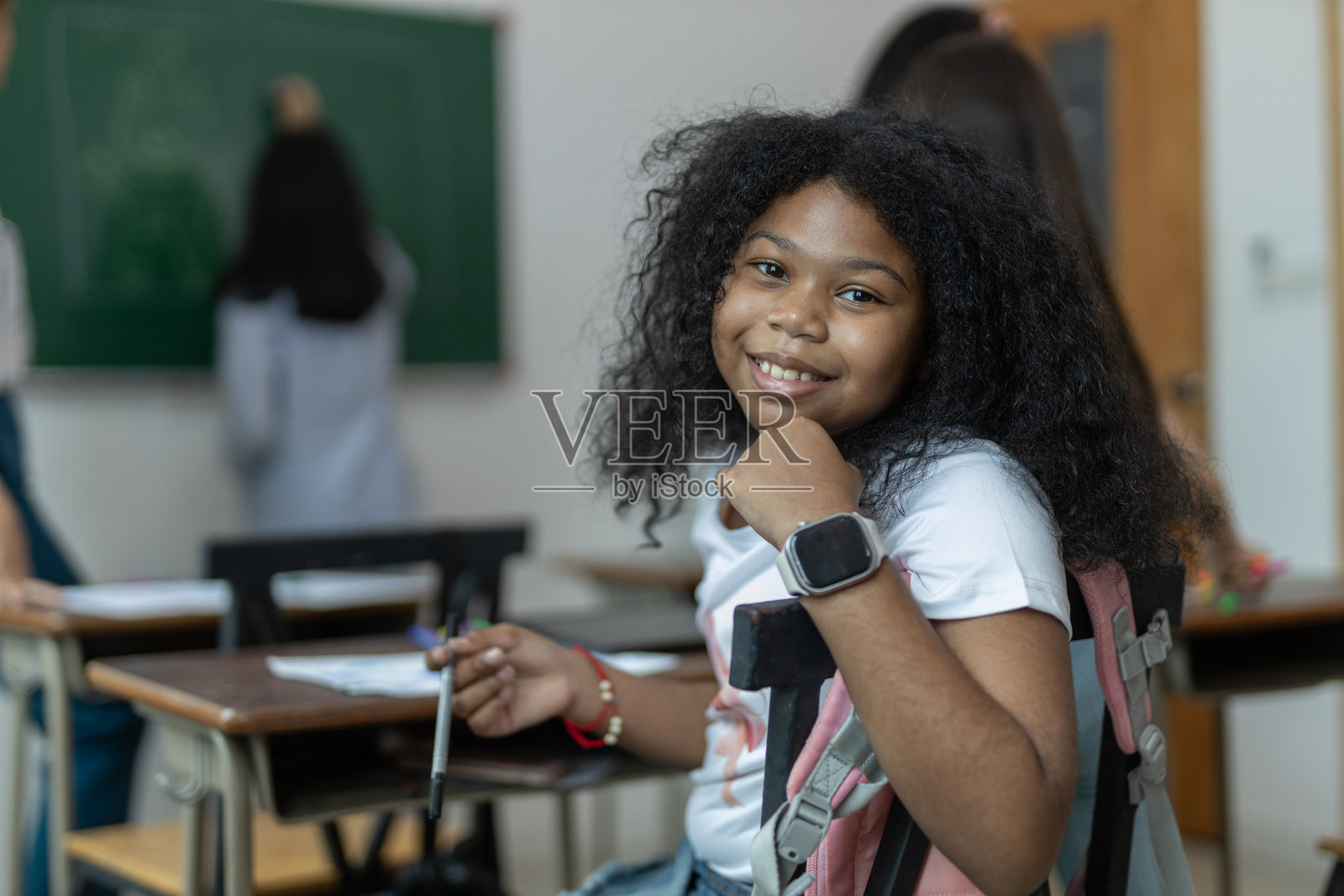 快乐的女学生在教室的课桌旁。儿童学生女孩教室学校教育。照片摄影图片