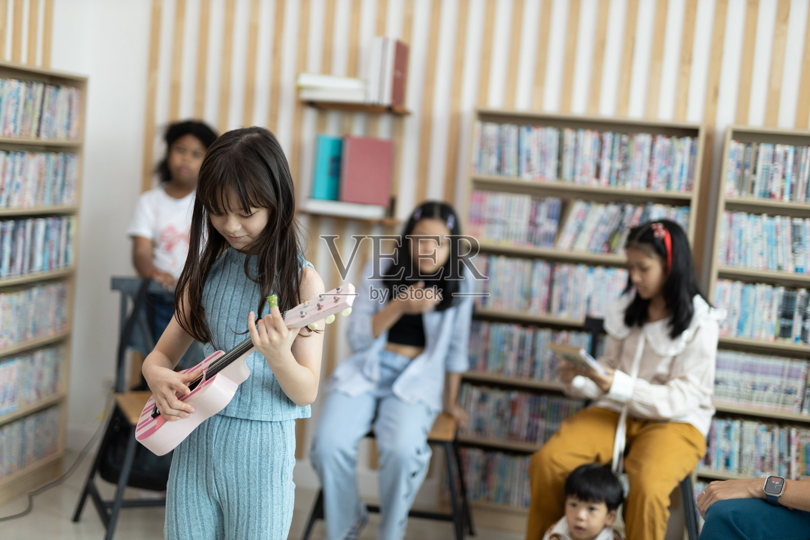 小学生在教室里学习弹奏尤克里里。快乐的女学生在学习。老师正在指导写作。重返校园的概念。照片摄影图片