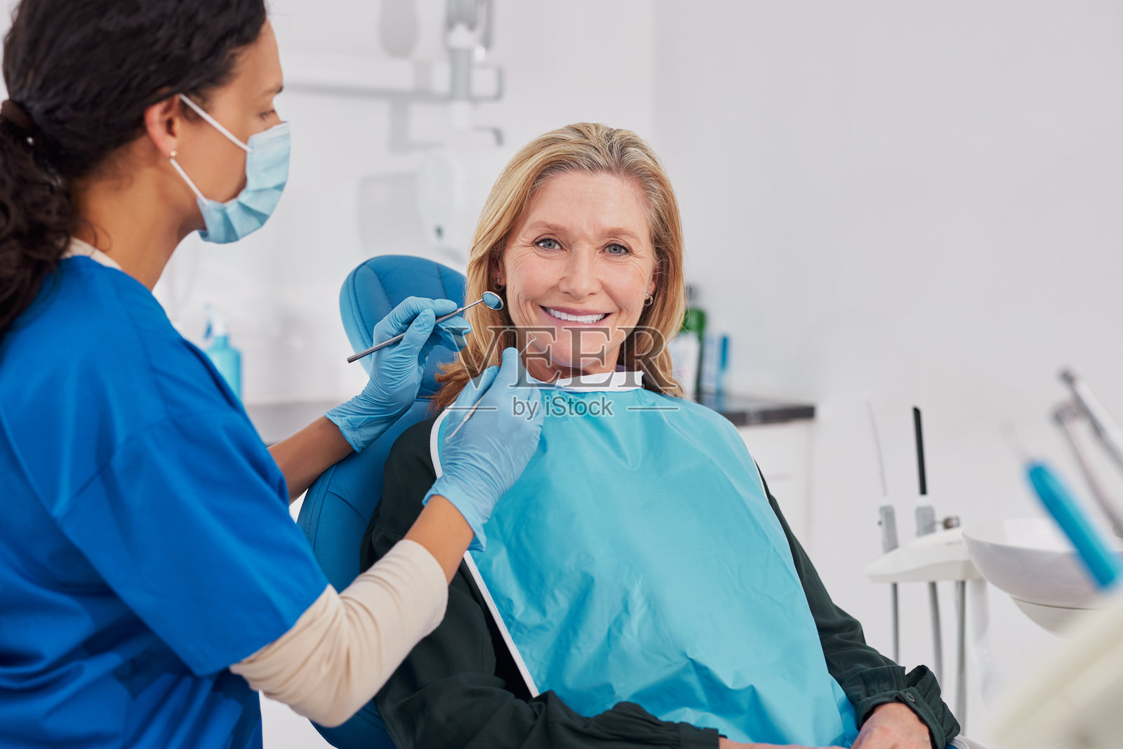 一位年长的女士微笑着看向镜头，她正身处一家牙科诊所照片摄影图片