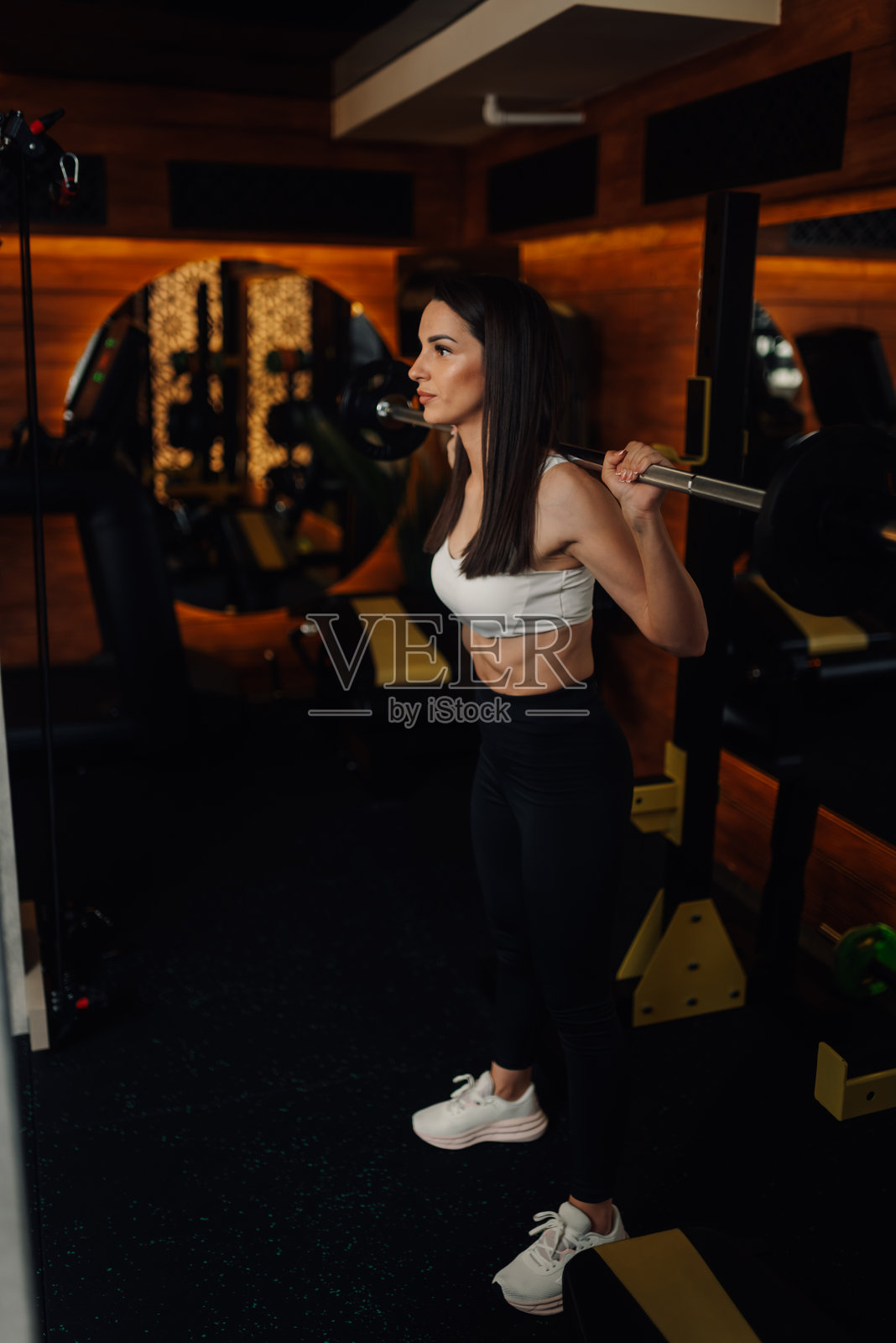 一位坚定的女运动员在现代健身房用杠铃做深蹲照片摄影图片