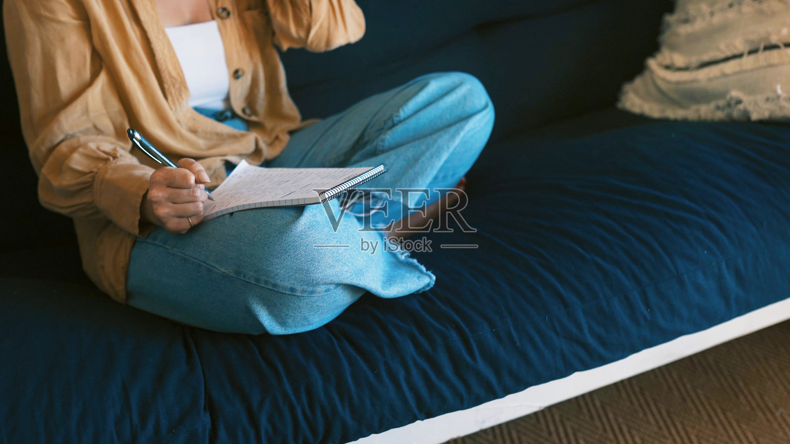 在沙发上写作、记录与双手，为小说在沙发上构思创意与计划，寻找灵感与想法。居家写作、作家与笔记本思考、放松与艺术家在沙发上进行项目。照片摄影图片