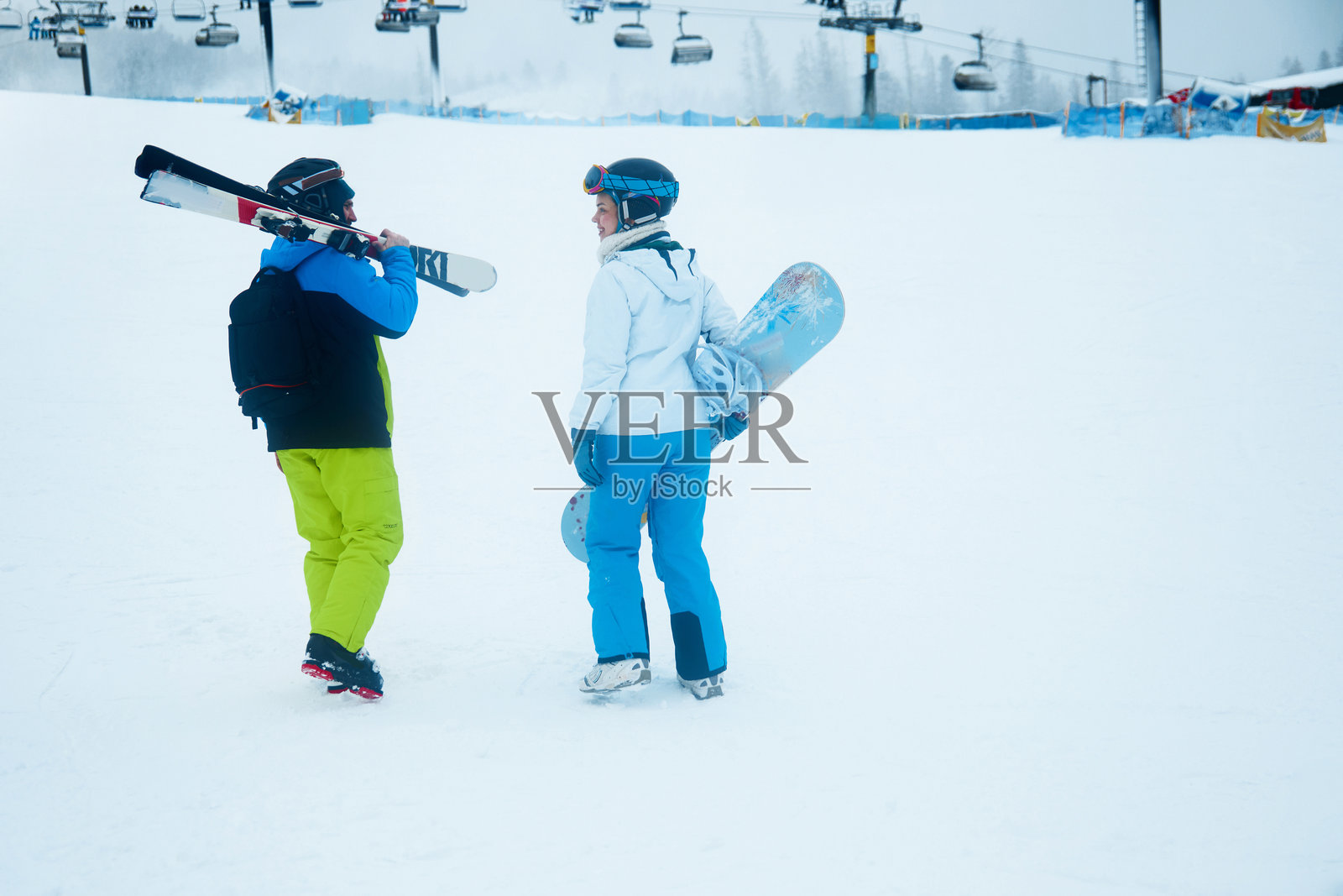 在雪天的早晨，滑雪者们在一个冬季度假村为雪坡上的一天做准备，他们鲜艳的装备在白雪的映衬下格外醒目。照片摄影图片