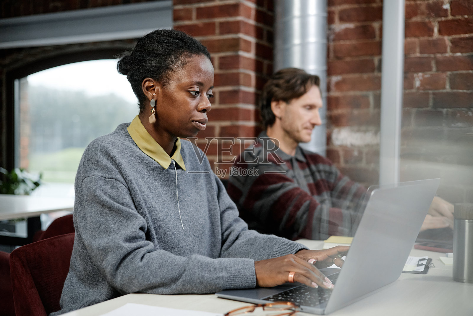 年轻的黑人女性在办公室里与白人男性一起使用笔记本电脑照片摄影图片