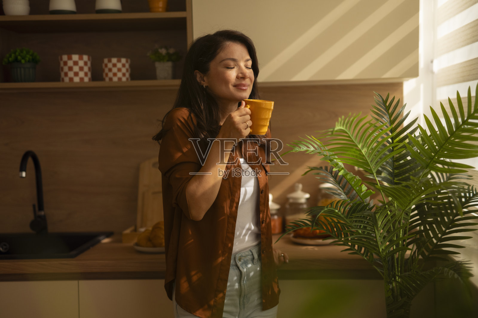 阳光明媚的厨房里，一位女士正在享用晨间咖啡照片摄影图片