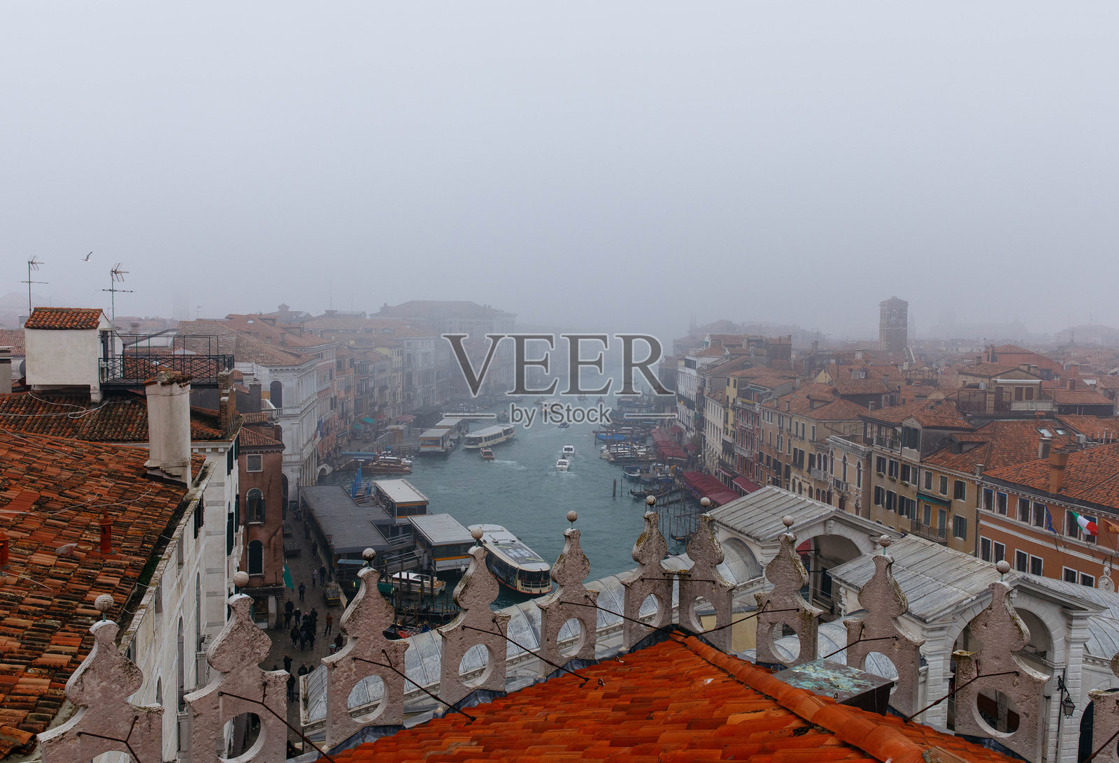 雾气笼罩下的威尼斯运河美景，展示着历史建筑和屋顶，船只穿梭于水道之间，营造出神秘的氛围照片摄影图片