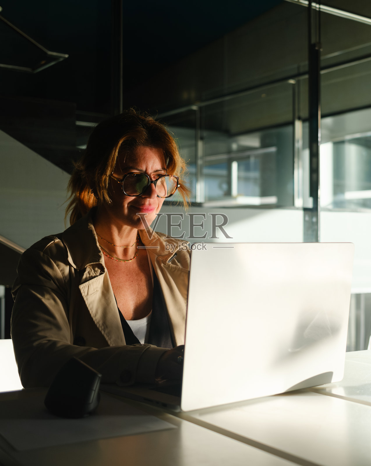 一位女士在现代办公室内部使用笔记本电脑工作照片摄影图片