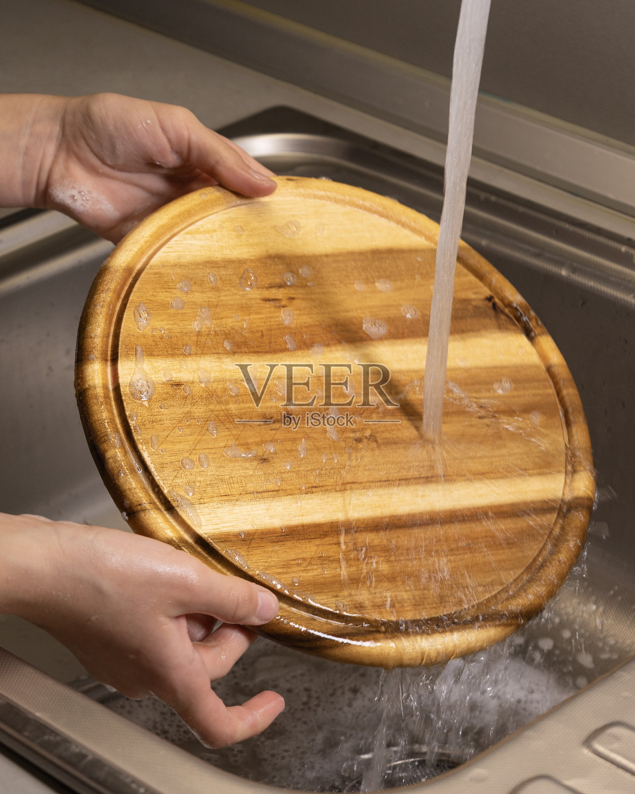 女孩在厨房水槽里清洗木质砧板照片摄影图片