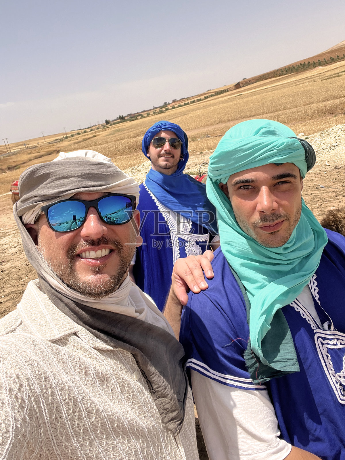 一群拉丁裔男性游客朋友在摩洛哥马拉喀什附近的撒哈拉沙漠骑骆驼游玩照片摄影图片