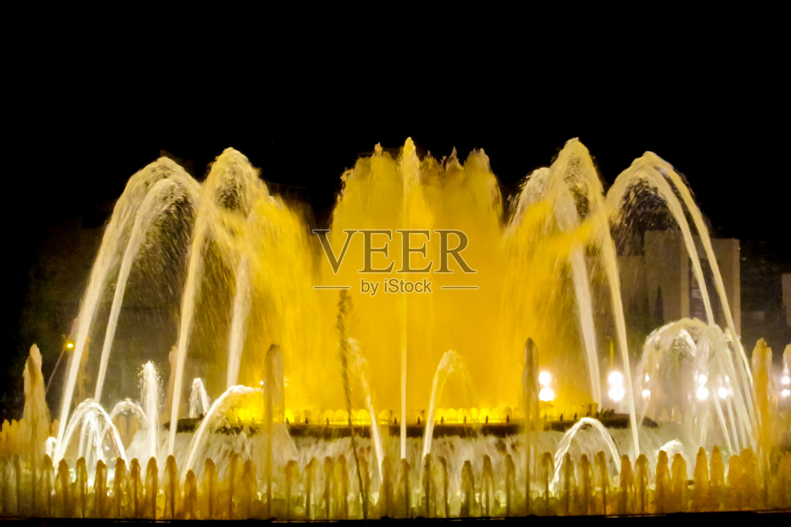 色彩斑斓的喷泉，明亮的喷射水柱在黑暗的背景下营造出充满活力的景象照片摄影图片