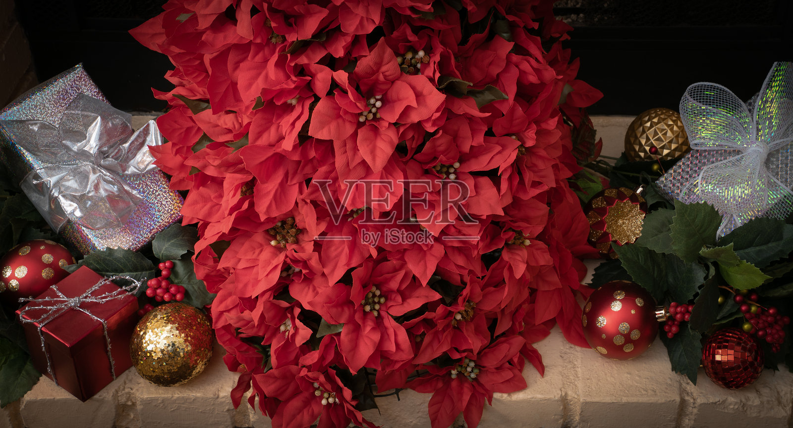 圣诞红摆放在壁炉上的炉架上，构成一棵圣诞树。照片摄影图片