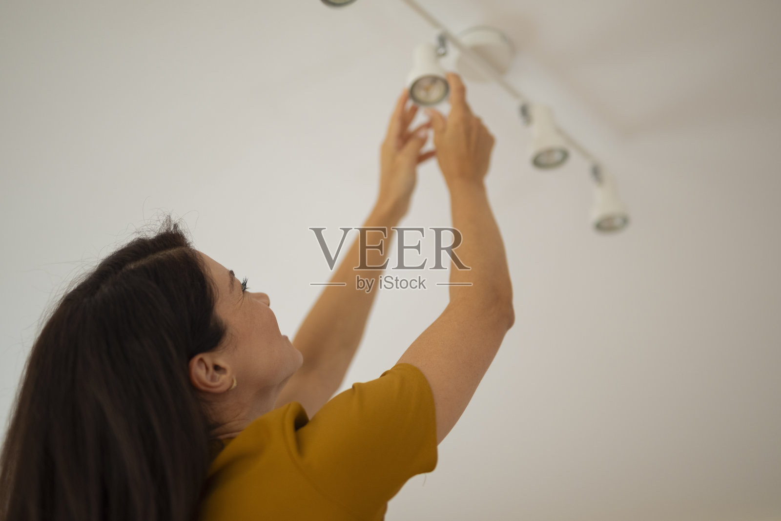 女子正在更换吸顶灯灯泡照片摄影图片