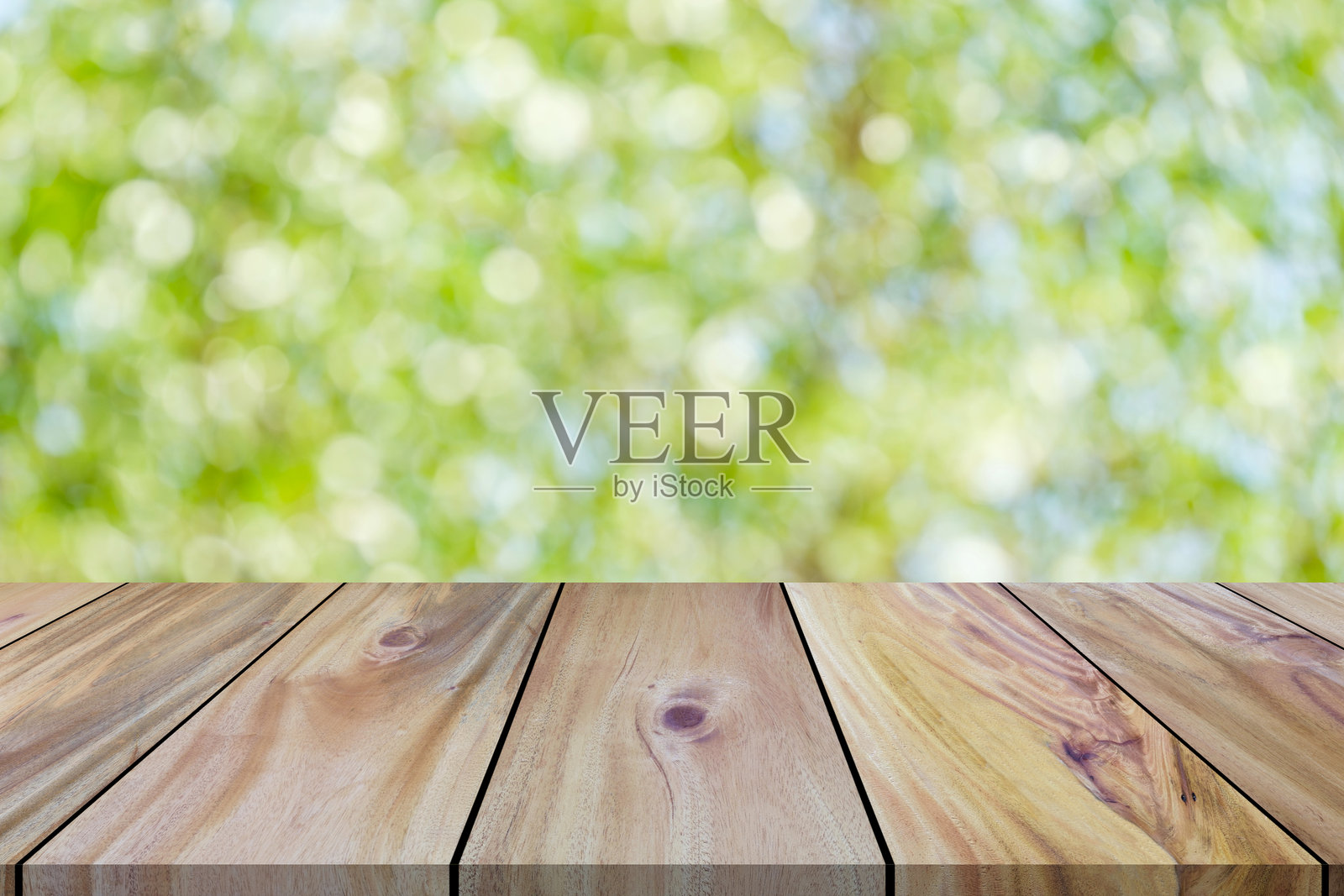 空木板长桌顶部，背景为模糊的新鲜绿叶散景照片摄影图片