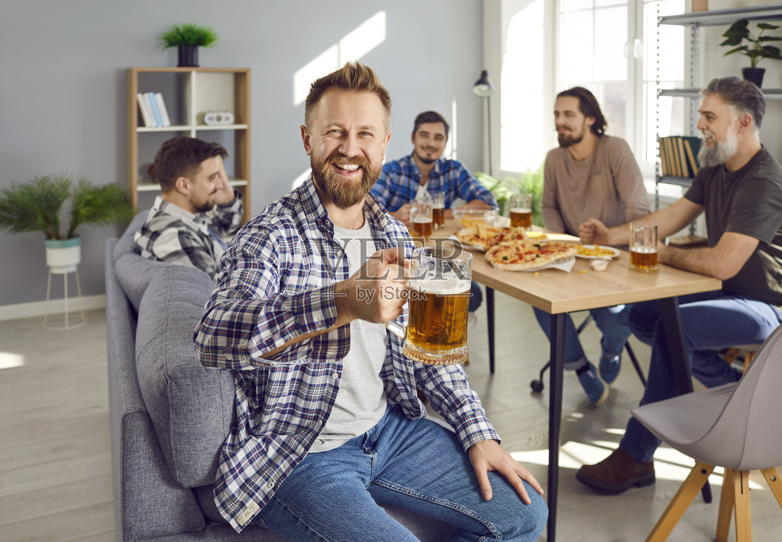 一个快乐、微笑的年轻人在派对上和朋友们一起玩乐、喝啤酒照片摄影图片