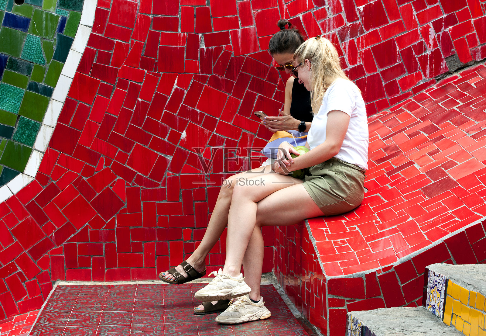 女孩们在巴西里约热内卢的塞勒隆阶梯（Escadaria Selarón）上查看自拍照片摄影图片