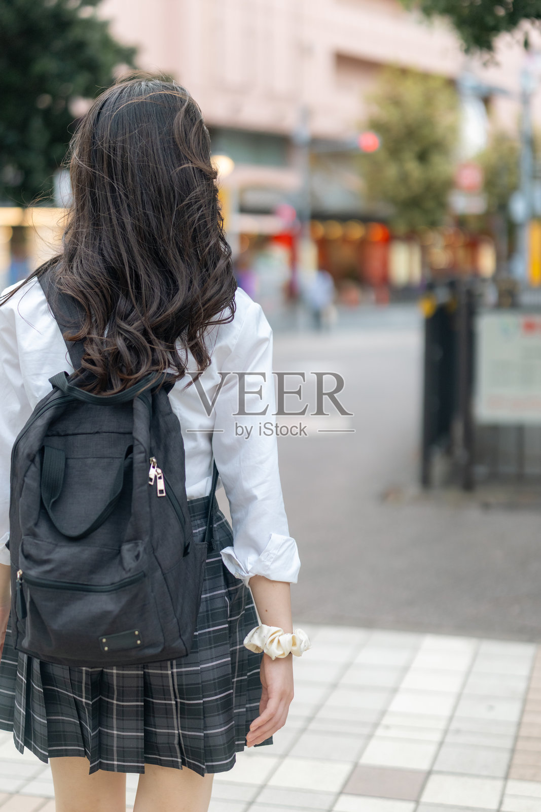 放学后，一名女高中生走在城市街道上的背影照片摄影图片